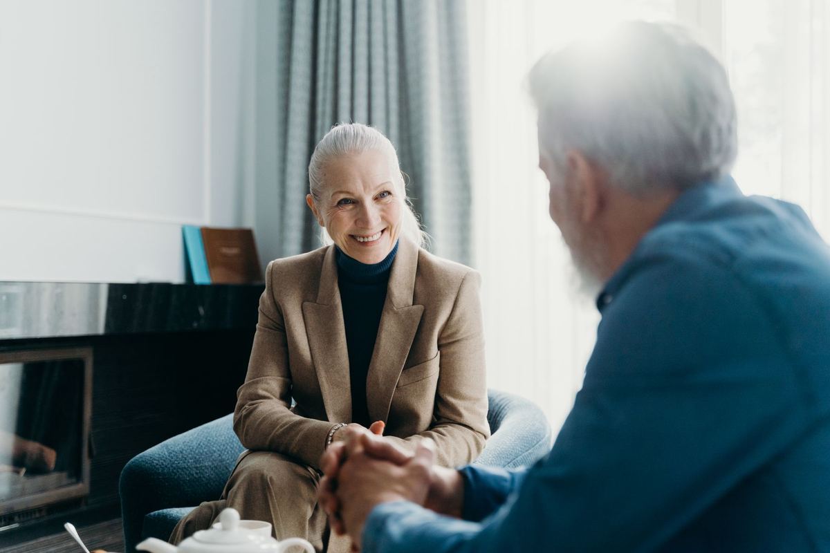 Two older people sitting and talking together at home
